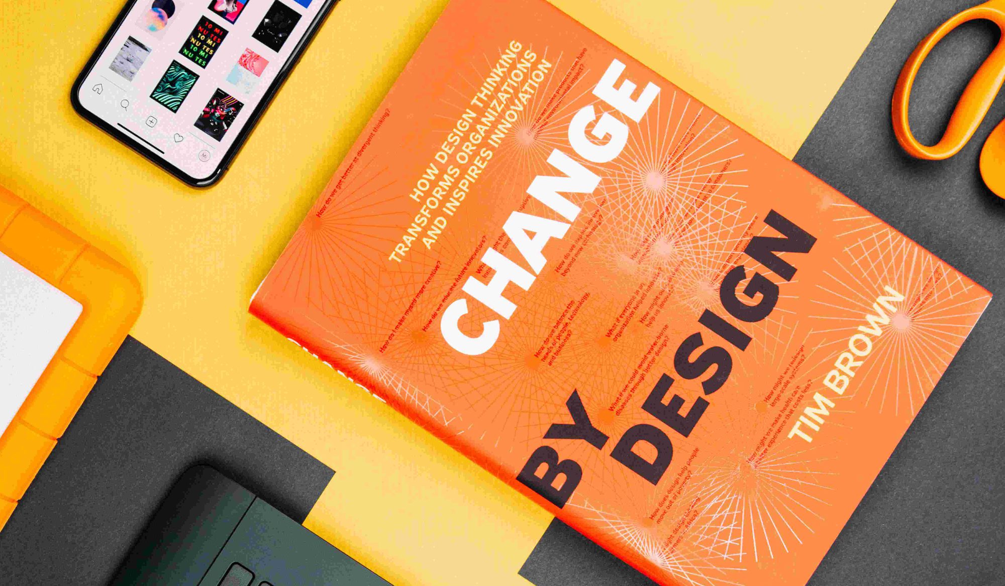 Graphic design book and phone with visual inspiration on colorful background.