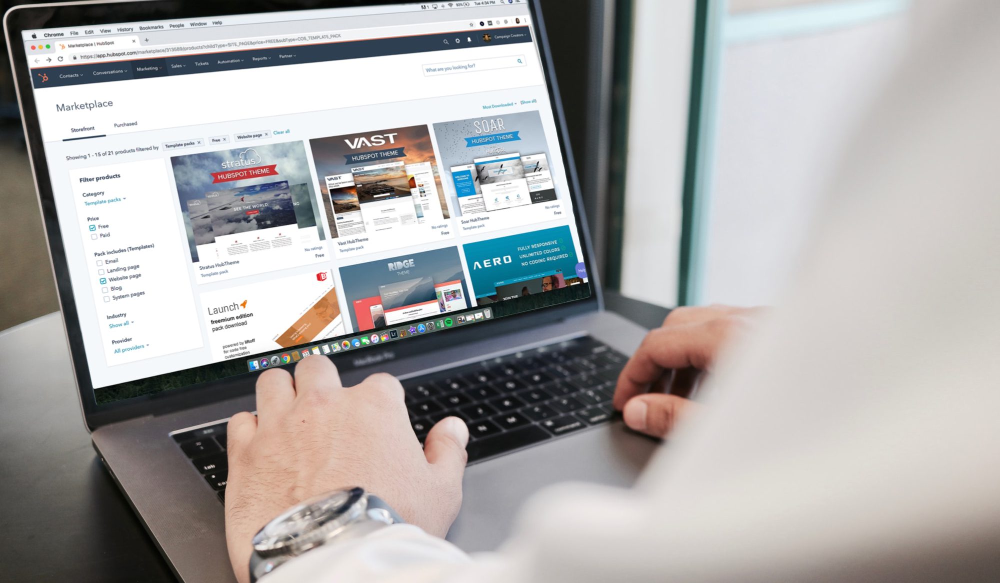 Person browsing web design templates on a laptop screen in an office setting.