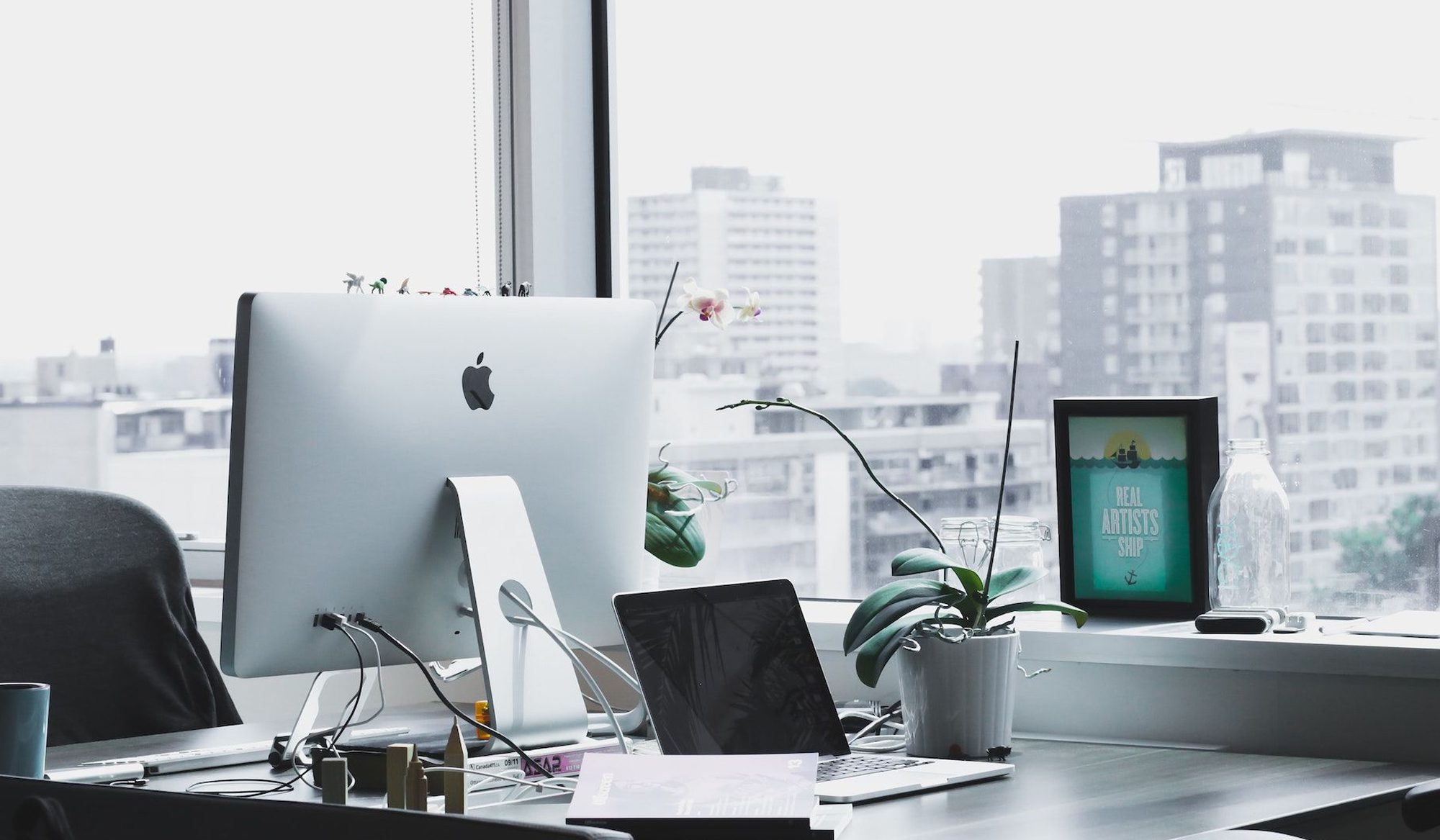 Modern desk setup with iMac overlooking a Singapore city skyline.