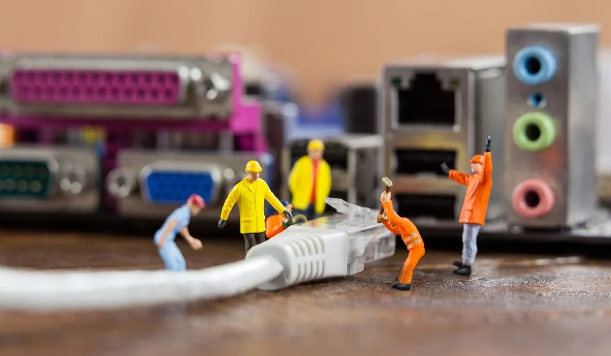 Miniature workers managing computer cables and connectors.