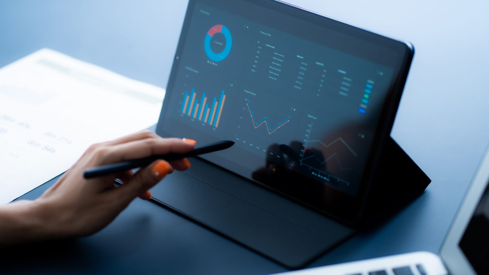 A person using a tablet with business analytics on the screen.