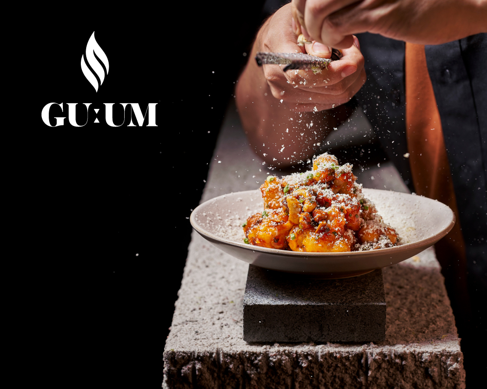 Chef garnishing a dish with grated cheese at a fine dining restaurant.