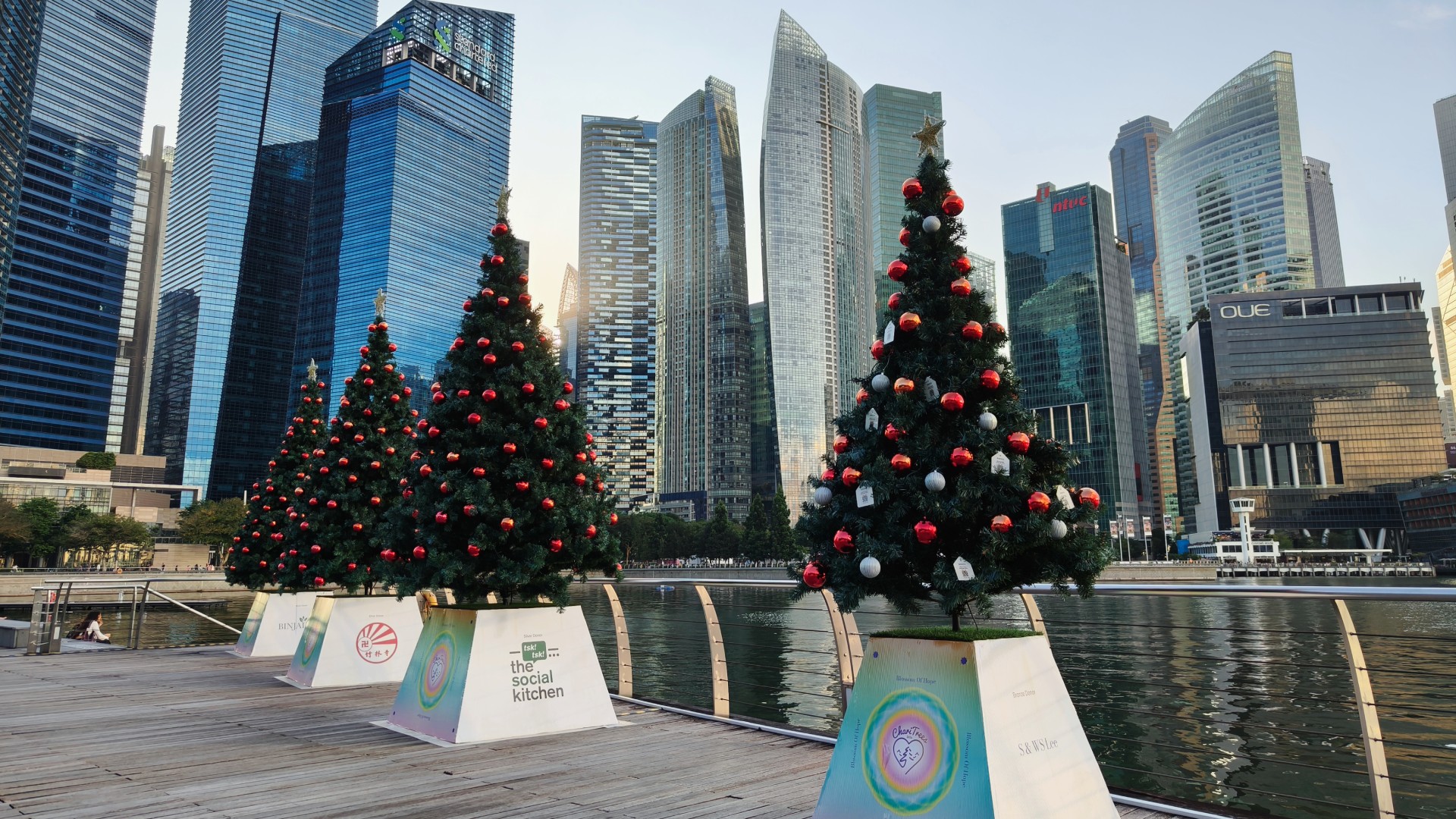 Christmas trees adorn the Singapore waterfront with towering skyscrapers behind.