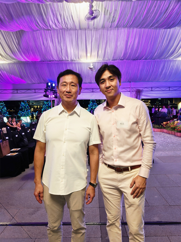Two individuals at a formal event under a tent with purple lighting.